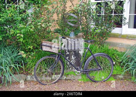 Ein altes Lieferfahrrad, das sich an eine Waffenarmillarsonnenuhr vor dem Killerton House, Exeter, Devon, England, Großbritannien, lehnt. Europa Stockfoto