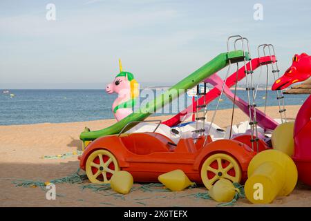 Tretboote am Strand. Einhorn in Pink mit rotem Auto und grüner Rutsche. Tretboot für Strand- und Strandunterhaltung. Stockfoto