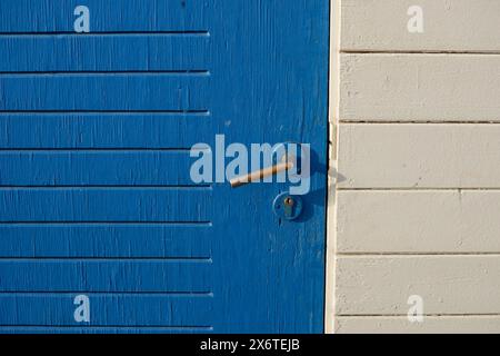 Alte verblasste lackierte Holzflächen. Blaue Tür und Türgriff. Stockfoto