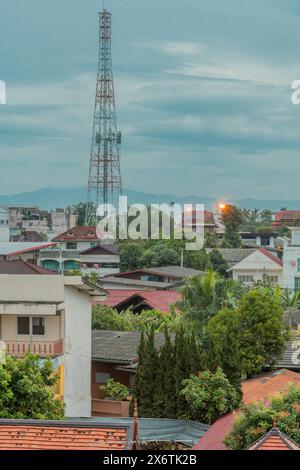 Kommunikationsturm über Dächern unter bewölktem Morgenhimmel. Aus dem Fenster im vierten Stock in Thailand Stockfoto