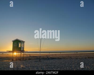 Eine Strandhütte bei Sonnenaufgang mit ruhiger Atmosphäre und weitem Meerblick, Sonnenuntergang am Strand mit Liegestühlen am Meer, Langeoog, Deutschland Stockfoto