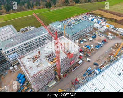Große Baustelle mit hohen Kränen und unfertigen Gebäuden in ländlicher Umgebung, umgeben von Fahrzeugen und Containern, Baustelle Stockfoto
