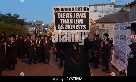 JERUSALEM - 14. MAI: Mitglied von Neturei Karta, eine ultraorthodoxe jüdische Bewegung innerhalb des antizionistischen Blocks trägt ein Schild mit der Aufschrift "Wir würden lieber als Juden sterben als als als Zionisten leben", während er an einer Kundgebung gegen die Schaffung des Staates Israel in der religiösen Nachbarschaft von MEA Shearim während der 76. Unabhängigkeit Israels teilnimmt Tag, während der anhaltenden Kämpfe zwischen Israel und der militanten Gruppe Hamas im Gazastreifen am 14. Mai 2024 in Jerusalem. Neturei Karta lehnt den Zionismus ab und fordert eine "friedliche Zerschlagung" des Staates Israel in dem Glauben, dass es Juden verboten ist, diesen zu haben Stockfoto