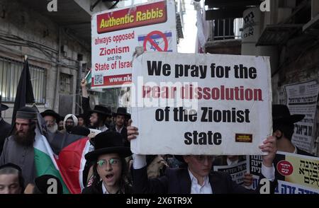 JERUSALEM - 14. MAI: Mitglieder von Neturei Karta, einer ultraorthodoxen jüdischen Randbewegung innerhalb des antizionistischen Blocks, halten palästinensische Fahnen und Zeichen gegen den Zionismus, während sie während einer Kundgebung gegen die Schaffung des Staates Israel durch die religiöse Nachbarschaft von MEA Shearim laufen. während Israel am 14. Mai 2024 in Jerusalem den 76. Unabhängigkeitstag feiert, während die Kämpfe zwischen Israel und der militanten Gruppe Hamas im Gazastreifen fortgesetzt werden. Neturei Karta lehnt den Zionismus ab und fordert eine "friedliche Zerschlagung" des Staates Israel, in dem Glauben, dass es Juden verboten ist, ihren eigenen Staat zu haben Stockfoto