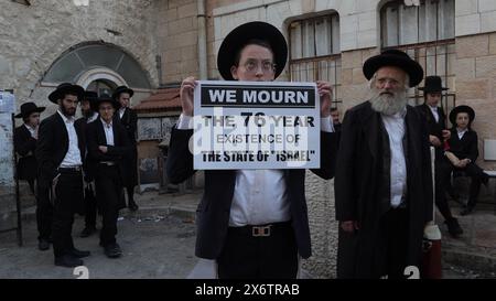 JERUSALEM - 14. MAI: Mitglied von Neturei Karta, eine ultra-orthodoxe jüdische Bewegung innerhalb des antizionistischen Blocks hält ein Schild mit der Aufschrift "Wir trauern um die 76-jährige Existenz des Staates Israel", während er an einer Kundgebung gegen die Schaffung des Staates Israel in der religiösen Nachbarschaft von MEA Shearim während der 76. Israels teilnimmt Unabhängigkeitstag am 14. Mai 2024 in Jerusalem, während der anhaltenden Kämpfe zwischen Israel und der militanten Gruppe Hamas im Gazastreifen. Neturei Karta lehnt den Zionismus ab und ruft zu einer "friedlichen Zerschlagung" des Staates Israel auf, in dem Glauben, dass es Juden verboten ist, ha zu haben Stockfoto