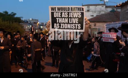 JERUSALEM - 14. MAI: Mitglied von Neturei Karta, eine ultraorthodoxe jüdische Bewegung innerhalb des antizionistischen Blocks trägt ein Schild mit der Aufschrift "Wir würden lieber als Juden sterben als als als Zionisten leben", während er an einer Kundgebung gegen die Schaffung des Staates Israel in der religiösen Nachbarschaft von MEA Shearim während der 76. Unabhängigkeit Israels teilnimmt Tag, während der anhaltenden Kämpfe zwischen Israel und der militanten Gruppe Hamas im Gazastreifen am 14. Mai 2024 in Jerusalem. Neturei Karta lehnt den Zionismus ab und fordert eine "friedliche Zerschlagung" des Staates Israel in dem Glauben, dass es Juden verboten ist, diesen zu haben Stockfoto