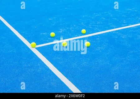 Fünf Paddeltennisbälle in der Nähe des Netzes eines blauen Paddeltennisplatzes, Racketsportkonzept Stockfoto