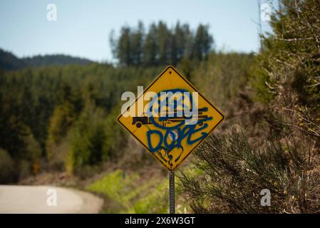 Ein Schild, das den Einsatz von Holzfällern auf einer Straße zwischen Lake Cowichan und Port Refrew in British Columbia, Kanada, warnt, wurde durch einen Anti-Lo-Mechanismus beschädigt Stockfoto