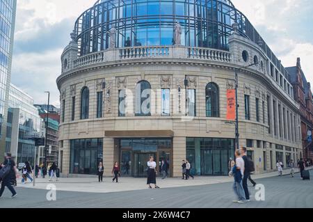 Eine einzige stationäre Frau steht auf dem City Square, Leeds, gegenüber dem Majestic, während andere um sie herum eilen. Frau am Telefon. Stockfoto