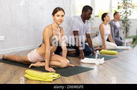 Sportliche Menschen verschiedener Nationalitäten üben Yoga-Unterricht im Sportclub Stockfoto