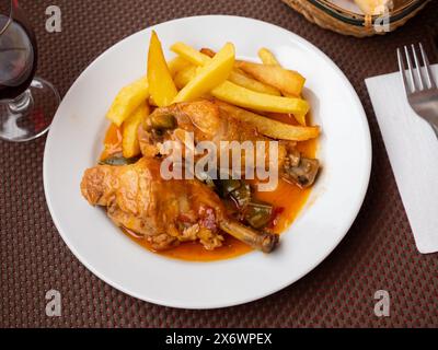 Pommes frites und ein Stück heißes gebratenes Hühnchen mit Chili werden auf einer großen weißen Platte serviert Stockfoto