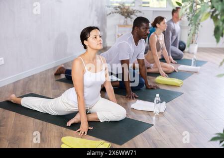 Sportliche Menschen verschiedener Nationalitäten üben Yoga-Unterricht im Sportclub Stockfoto