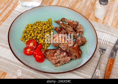 Über offenem Feuer gekochtes Rindfleisch mit appetitlicher Kruste und dunklen Streifen mit Kirschtomaten und Bohnen Stockfoto