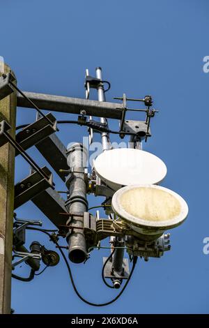 Nahaufnahme eines Telekommunikationsturms mit verschiedenen Antennen und verwitterten Schüsseln, klarer blauer Himmel im Hintergrund Stockfoto