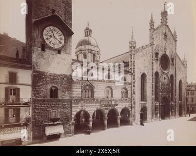 Fassade und Kuppel der Kathedrale von Como, Blick auf die Fassade und Kuppel des Doms in Como, Italien. Foto von schräg vor der Tür, mit der Kirchenglocke deutlich im Blick. Außerdem ein Uhrmacher/Optiker und ein Regenschirmladen unter dem Turm und links im Bild., Foto, anonym, Como, 1851 - 1900, Papier, Albumendruck, Höhe, 204 mm x Breite, 267 mm Stockfoto