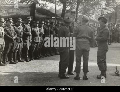 Deutsche Kriegsgefangene, deutsche Kriegsgefangene, die von Engländern bewacht werden? Soldaten. Im Vordergrund vier alliierte Soldaten. Am Ende der Reihe sind die deutschen Kriegsgefangenen. Foto, anonym, Niederlande, Mai 1945, fotografischer Träger, Höhe, 13 cm x Breite, 17,5 cm Stockfoto