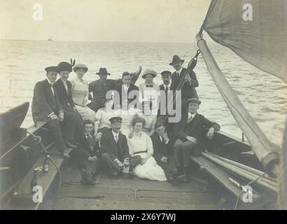 Gruppenporträt einer Gruppe auf einem Segelschiff, sieben Frauen und neun Männer sitzen auf dem Heck eines Segelschiffes. Bierflaschen links auf der Couch., Foto, anonym, Niederlande, ca. 1915 - ca. 1920, fotografischer Träger, Gelatinedruck, Höhe, 116 mm x Breite, 157 mm Stockfoto