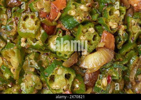 Gebratenes Okra oder Okro-Gericht in Nahaufnahme umrühren, alias Frauenfinger, temperiertes vegetarisches Curry mit Gewürzen im Vollformat, Essenshintergrund Stockfoto