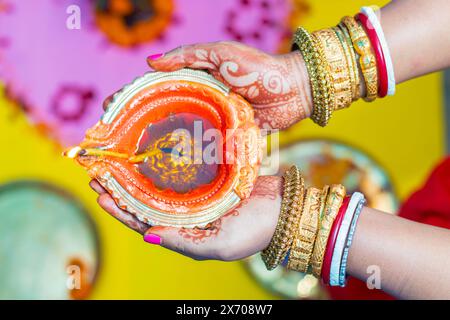 Eine indische Dame hält mit Kerzenlicht Diya auf schwarzem Hintergrund. Stockfoto