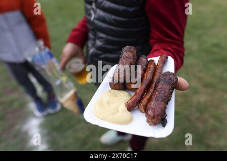 Die Person hält traditionelle rumänische Mici (mititei), gegrillte Hackfleischrollen in zylindrischer Form, Susages und Senf in der Hand. Stockfoto