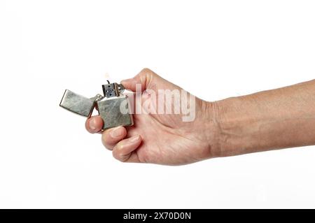 Handgriff für Feuerzeug, isoliert auf weißem Hintergrund. Das Feuer brennt. Kühles Metallic-Feuerzeug in der Hand Stockfoto