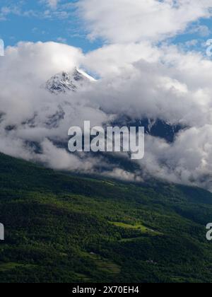 Dramatische Wolken über alpinen Bergen oberhalb von Fenis mit Wald und einer Lichtung darunter im Aostatal, NW Italien. 16.-17. Mai 2024 Stockfoto