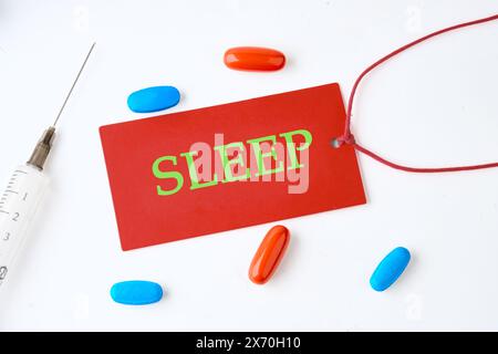 Kopierbereich. Gesunder Lebensstil und Schlafkonzept. SCHLAFTEXT auf roter Karte auf hellem Hintergrund mit Pillen in der Komposition Stockfoto