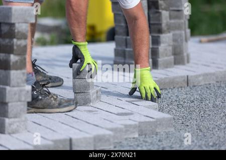 Arbeiter, der einen neuen, aus Betonblöcken bestehenden Bürgersteig mit Verbindungsteig anfertigt Stockfoto