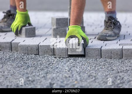 Arbeiter, der einen neuen, aus Betonblöcken bestehenden Bürgersteig mit Verbindungsteig anfertigt Stockfoto