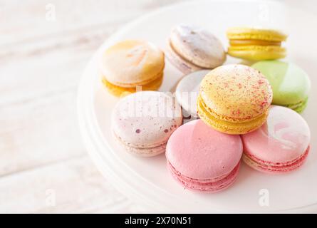 Mehrfarbige Macarons auf Holzhintergrund mit sanften Lichtern und Schatten. Sanfte Makronen auf dem Tisch auf hellem Hintergrund. Stockfoto