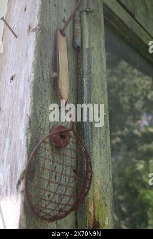 Sehr altes Sieb mit rostigem Griff, das an der Wand hängt Stockfoto