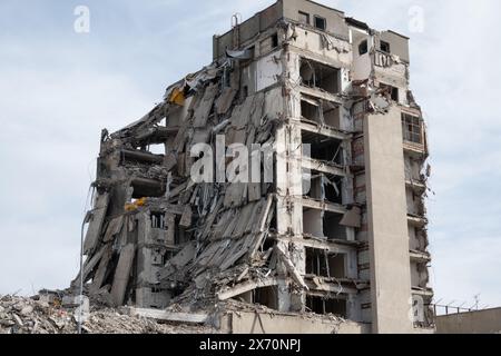 Ein teilweise eingestürztes Gebäude in einer städtischen Umgebung, das erhebliche Schäden und Zerstörungen aufweist. Das Bild zeigt die Folgen einer Katastrophe oder eines Abbruchs. Stockfoto