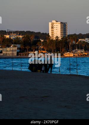 Silhouetten von Fischern am Strand von Cambrils, Spanien. Angeln vom Strand aus mit einer Rute Stockfoto