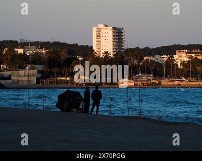 Silhouetten von Fischern am Strand von Cambrils, Spanien. Angeln vom Strand aus mit einer Rute Stockfoto