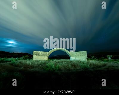 Langzeitbelichtungslandschaft der Brückenruine mit Reflexion des fließenden Wolkenhimmels bei Nacht Stockfoto