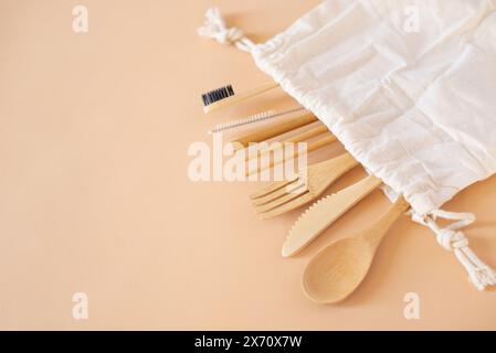 Umweltfreundliche Tasche und Bambusbesteck mit Zahnbürste auf beigefarbenem Hintergrund für grünes Leben und Zero Waste Konzept. Draufsicht. Stockfoto