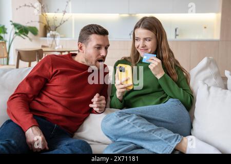 Ich bin froh, dass ein interessiertes Paar online einkaufen kann. Kaufen Sie Ihr Mobiltelefon mit Kreditkarte zu Hause Stockfoto