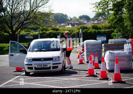 Leute sammeln Wasser in Flaschen auf dem Broadsands Parkplatz in Paignton. Rund 16.000 Haushalten und Unternehmen in der Region Brixham in Devon wurde gesagt, ihr Leitungswasser nicht zu trinken, ohne es zuerst zu kochen und zu kühlen, nachdem kleine Spuren eines Parasiten im lokalen Wassernetz entdeckt wurden. Bilddatum: Freitag, 17. Mai 2024. Stockfoto