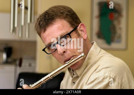 Mann, der die Flöte spielt Porträt eines 39-jährigen Mannes, der eine Brille trägt und die Flöte spielt. Dieses Musikinstrument wird meist mit Frauen in Verbindung gebracht. Durch SRC. Tilburg, Niederlande. MRYES Tilburg Studio Tuinstraat Noord-Brabant Nederland Copyright: XGuidoxKoppesxPhotox Stockfoto