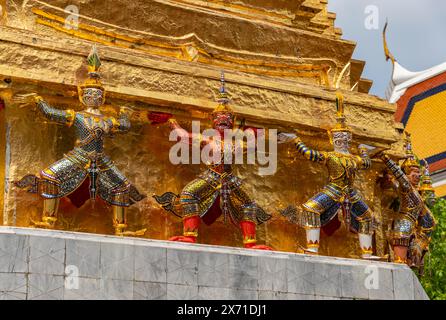 Ein Bild von Statuen am Fuße eines goldenen Chedi im Großen Palast in Bangkok. Stockfoto