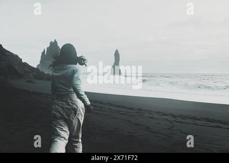 Kaukasische Touristenfrau in hellen Kleidern, Spaziergang, aufgeregt Besuchen Sie den berühmten schwarzen Sandstrand Reynisfjara allein in der Nähe von Wellen und berühmten Felsklippen in BA Stockfoto