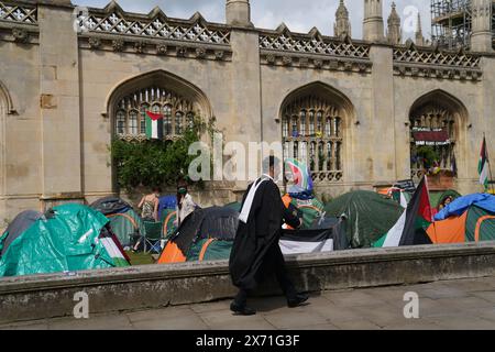 Ein Student läuft in der Nähe eines Zeltlagers, der sich gegen den Gaza-Konflikt auf dem Gelände der Universität Cambridge aussprach. Die Abschlussfeier wurde wegen des propalästinensischen Protestlagers verlegt. Bilddatum: Freitag, 17. Mai 2024. Stockfoto