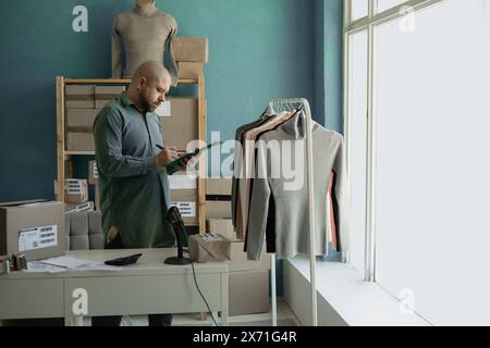 Start. Kleine Unternehmen. Der Ladenbesitzer prüft die Verfügbarkeit von Kleidung für die Lieferung an den Kunden. Stockfoto