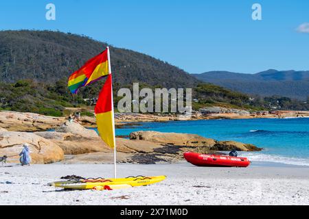 Surfen Sie in Waubs Bay, Bicheno Beach East Coast Tasmania auf der lebensrettenden Flagge auf weißem Sand Stockfoto