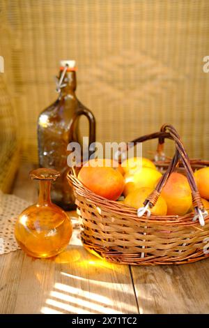 Reife Äpfel im Korb, Apfelsaft, Flasche Apfelwein, rustikaler Tisch mit warmem Sonnenlicht, Konzepternten, Fülle, natürliche Schönheit, Farm-to-Tabl Stockfoto