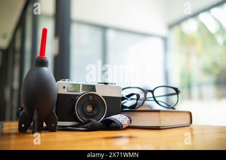 Eine Vintage-Filmkamera sitzt auf einem Tisch in einem Büro und ein Buch hebt sich im Hintergrund hervor. Eine Vintage-Filmkamera mit schlichtem Design sitzt auf einem Tisch Stockfoto