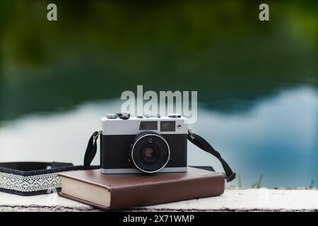 Eine Vintage-Filmkamera sitzt auf einem Tisch in einem Büro und ein Buch hebt sich im Hintergrund hervor. Eine Vintage-Filmkamera mit schlichtem Design sitzt auf einem Tisch Stockfoto