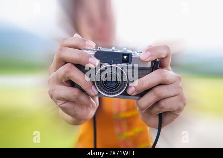 Die junge Fotografin hält eine Filmkamera im Vintage-Stil in der Hand und inspiziert die Filmkamera, um sie zu verwenden, nachdem Filmkameras bei der Fotografie populär geworden sind Stockfoto