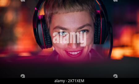 Nahaufnahme Porträt einer stilvollen jungen Frau mit kurzen Haaren, die am Abend zu Hause Online-Computervideospiel spielt. Gamer diskutieren Taktiken mit Teamkollegen, während er mit dem Headset spricht. Stockfoto