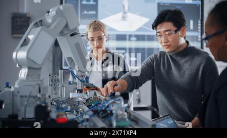 Bionische Gliedmaßen bewegen sich auf unterschiedliche Weise, während verschiedene Schüler im Chat mit schwarzem Lehrer Vermutungen und Hypothesen machen. Menschen, die gemeinsam an einem Engineering-Projekt in der Schule in Workshop arbeiten. Stockfoto